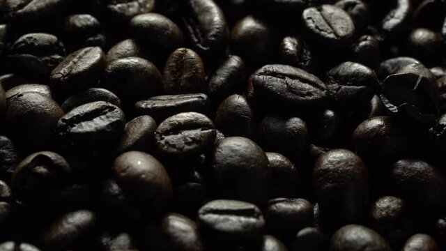 Coffee beans in rotation. Mixed Robusta and Arabica roasted Coffee beans. Coffee background. Coffee backdrop. Close up.