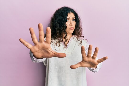 Young brunette woman with curly hair wearing casual clothes doing stop gesture with hands palms, angry and frustration expression
