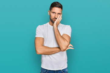 Handsome man with beard wearing casual white t shirt thinking looking tired and bored with depression problems with crossed arms.