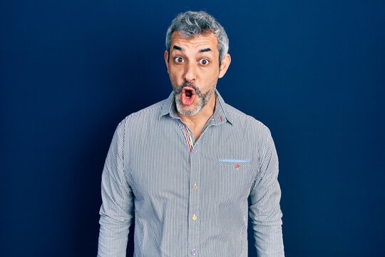 Handsome middle age man with grey hair wearing business shirt afraid and shocked with surprise expression, fear and excited face.