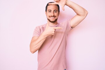 Young handsome man wearing casual tshirt smiling making frame with hands and fingers with happy face. creativity and photography concept.