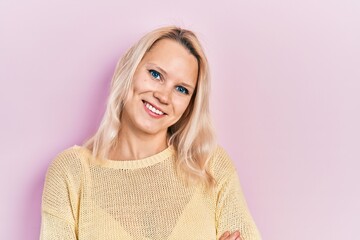 Fototapeta premium Beautiful caucasian blonde woman wearing casual winter sweater happy face smiling with crossed arms looking at the camera. positive person.