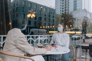 Friends girls met in a cafe. Wear medical protective masks.