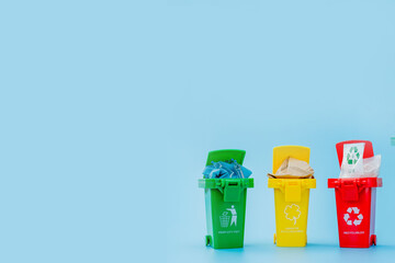 Yellow, green and red recycle bins with recycle symbol on blue background. Keep city tidy, Leaves the recycling symbol. Nature protection concept