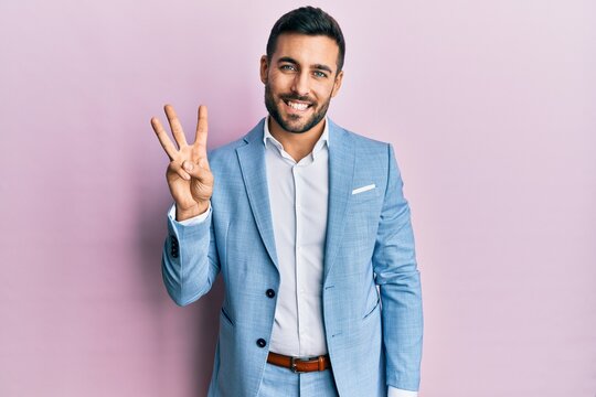 Young hispanic businessman wearing business jacket showing and pointing up with fingers number three while smiling confident and happy.
