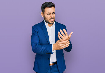 Young hispanic man wearing business jacket suffering pain on hands and fingers, arthritis...