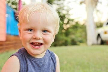 Toddler boy with big smile outdoors with nature background