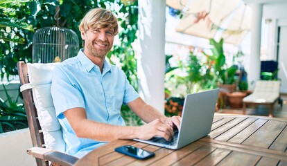 Fototapeta premium Middle age handsome man working at home using computer laptop