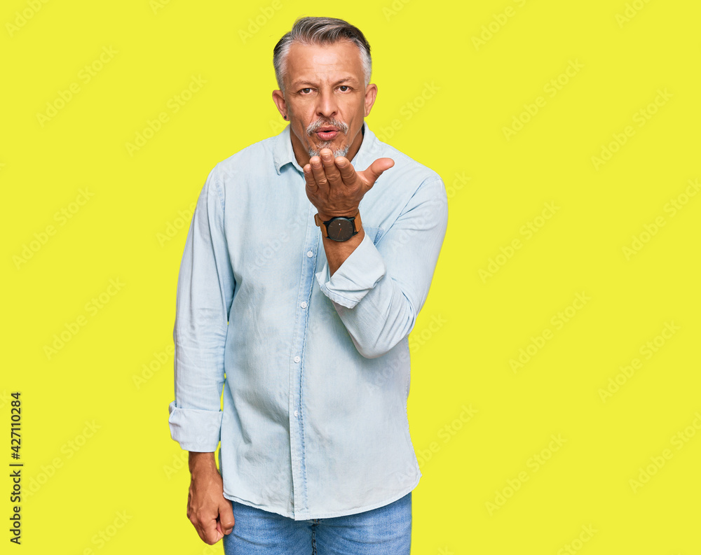 Sticker middle age grey-haired man wearing casual clothes looking at the camera blowing a kiss with hand on 