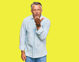 Middle age grey-haired man wearing casual clothes looking at the camera blowing a kiss with hand on air being lovely and sexy. love expression.