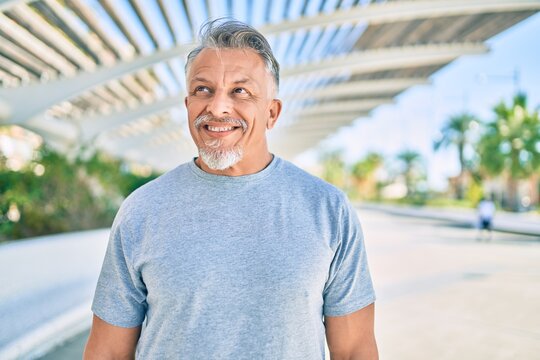 Middle age hispanic grey-haired man smiling happy standing at the city.