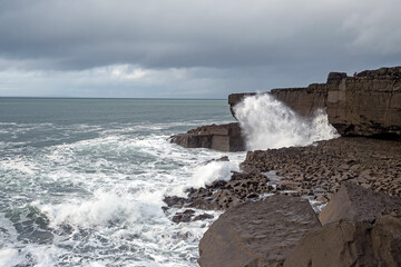 Power full ocean wave breaks on rock shore line creating big splash of water. Storm on West coast of Ireland. Power of Nature concept.