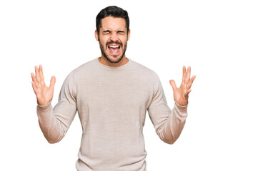 Young hispanic man wearing casual clothes celebrating mad and crazy for success with arms raised...