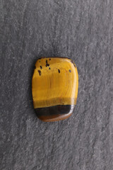 Tiger's Eye jewel texture on black stone background. Macro closeup.