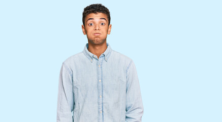 Young handsome african american man wearing casual clothes puffing cheeks with funny face. mouth...