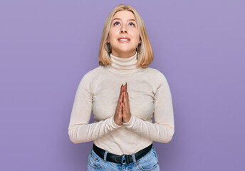 Young blonde woman wearing casual clothes begging and praying with hands together with hope...