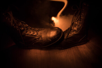 War concept. Old military shoe in a dark toned foggy background. Creative concept of conflict...