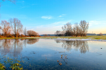 spring thaws on a green field, reflected in water