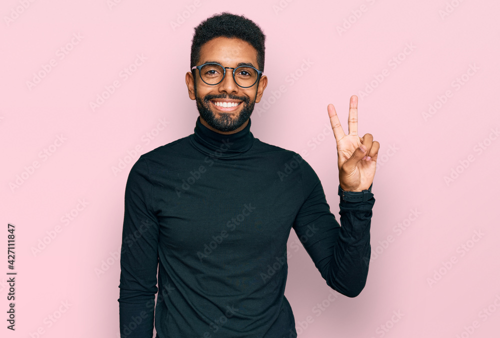 Poster Young african american man wearing casual clothes smiling with happy face winking at the camera doing victory sign. number two.