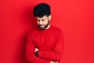 Fototapeta na wymiar Young arab man with beard wearing casual red sweater with hand on stomach because nausea, painful disease feeling unwell. ache concept.