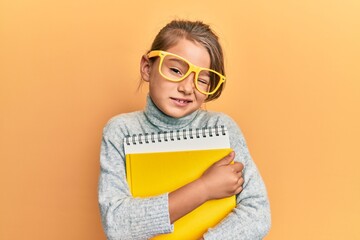Little beautiful girl wearing glasses and holding books winking looking at the camera with sexy...