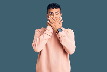 Young hispanic man wearing casual clothes shocked covering mouth with hands for mistake. secret concept.