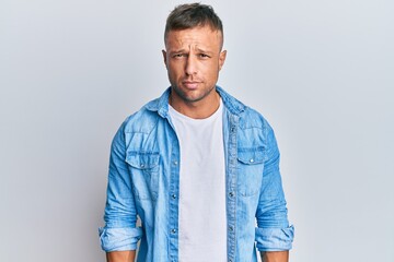 Handsome muscle man wearing casual denim jacket skeptic and nervous, frowning upset because of...
