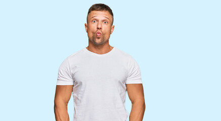 Handsome muscle man wearing casual white tshirt making fish face with lips, crazy and comical gesture. funny expression.