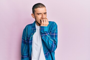 Fototapeta premium Hispanic young man wearing casual clothes looking stressed and nervous with hands on mouth biting nails. anxiety problem.