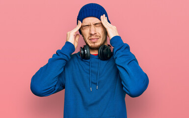 Hispanic young man wearing sweatshirt and wool hat suffering from headache desperate and stressed because pain and migraine. hands on head.