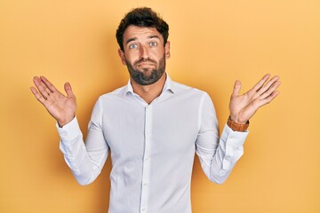 Handsome man with beard wearing casual white t shirt clueless and confused with open arms, no idea and doubtful face.