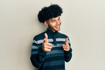 Young african american man with afro hair wearing casual clothes pointing fingers to camera with...