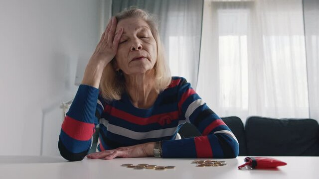 Worried old woman running out of money. Counting coins on the table. High quality 4k footage