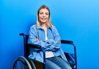 Beautiful caucasian woman sitting on wheelchair happy face smiling with crossed arms looking at the...