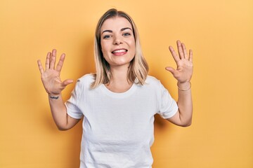 Beautiful caucasian woman wearing casual white t shirt showing and pointing up with fingers number ten while smiling confident and happy.