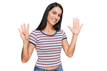 Young hispanic girl wearing casual striped t shirt showing and pointing up with fingers number nine while smiling confident and happy.