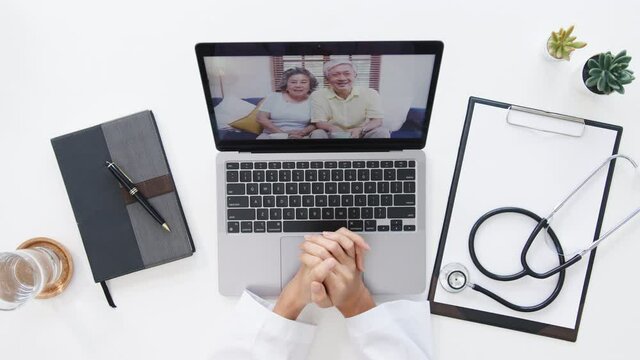Top view of young Asia female doctor in medical uniform with stethoscope using laptop talking video conference call with patient at desk in health clinic or hospital. Consulting and therapy concept.