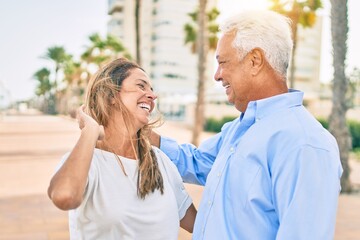 Middle age hispanic couple smiling happy hugging at the promenade.
