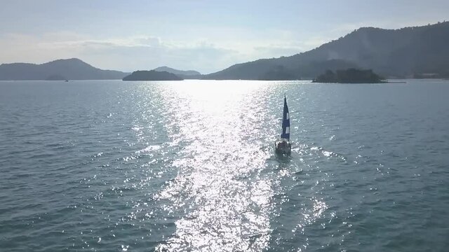 Aerial and slow motion view of a sailboat sailing in the limpid waters of the bay of Angra dos Reis, Rio de Janeiro, Brazil