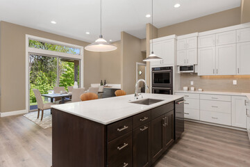Beautiful kitchen in new luxury home with large island, pendant lights, and stainless steel appliances. Shows eating nook and sliding glass doors leading out to backyard