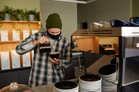 Waist up portrait of male barista wearing mask while making fresh coffee in coffee shop or cafe, copy space