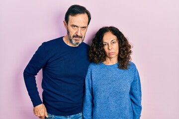 Middle age couple of hispanic woman and man hugging and standing together skeptic and nervous, frowning upset because of problem. negative person.