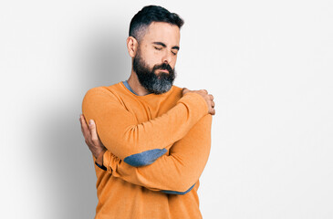 Hispanic man with beard wearing casual winter sweater hugging oneself happy and positive, smiling confident. self love and self care