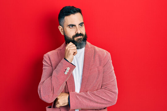 Young hispanic man wearing business clothes thinking concentrated about doubt with finger on chin and looking up wondering