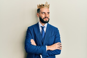 Young business man with beard wearing king crown smiling looking to the side and staring away...
