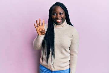 Young black woman with braids wearing casual winter sweater showing and pointing up with fingers number four while smiling confident and happy.