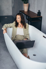 Woman sitting in a suit in the bathtub pondering her work