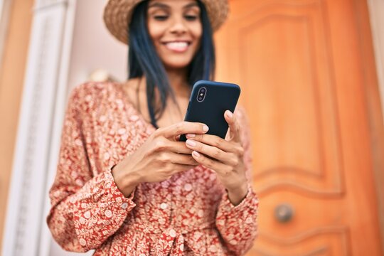 Young african american tourist woman on vacation smiling happy using smartphone at the city.