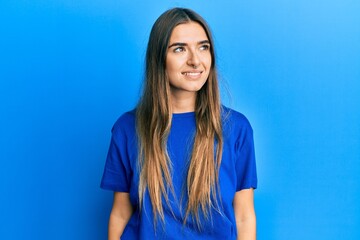 Young hispanic woman wearing casual clothes looking away to side with smile on face, natural expression. laughing confident.