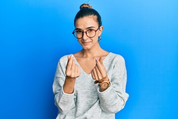 Young hispanic woman wearing casual clothes doing money gesture with hands, asking for salary...